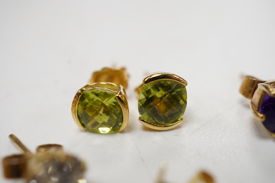 A pair of chequerboard cut peridot set 18ct stud earrings, a pair of amethyst set 9ct stud earrings and three costume pairs of earrings.